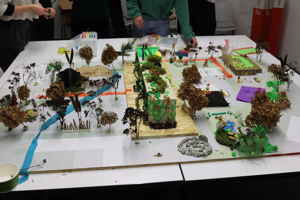 You can see a self-built model of the school site made of wood, cardboard, modelling clay and plants on a table.