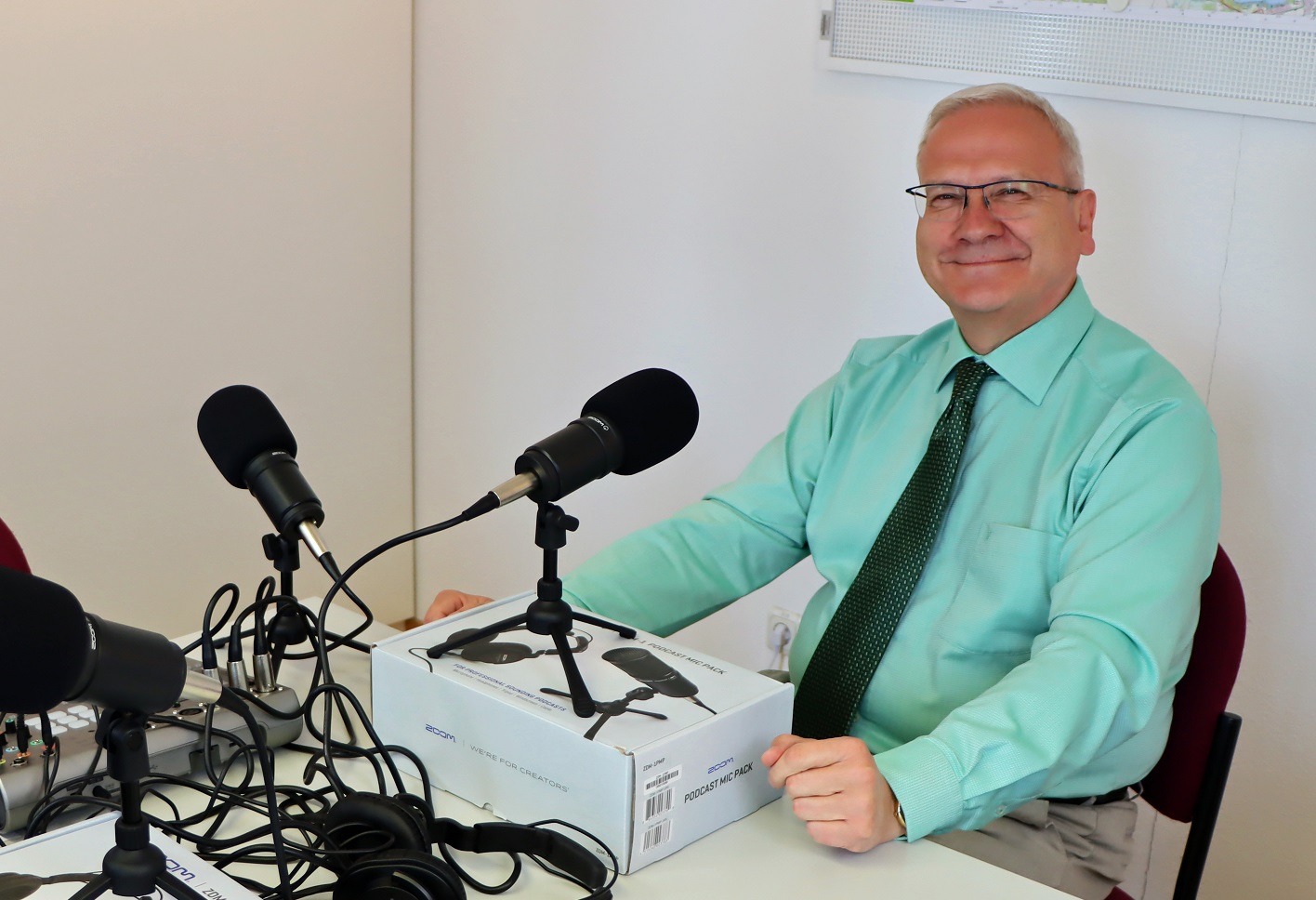 Oberbürgermeister Torsten Ruban-Zeh sitzt vor einem Mirkofon während der Audio-Produktion des Smalltalks und lacht in die Kamera.